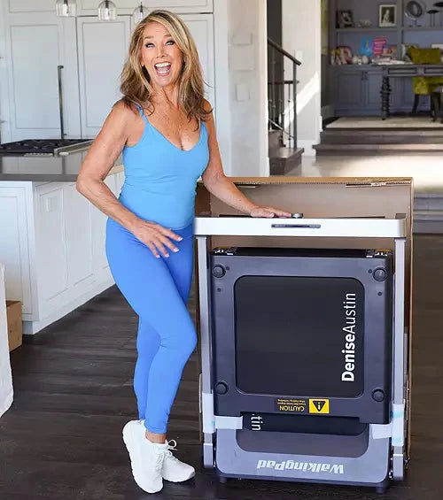 Denise Austin next to the Denise Austin 2.0 Foldable Treadmill, showing off the folding capabilities.